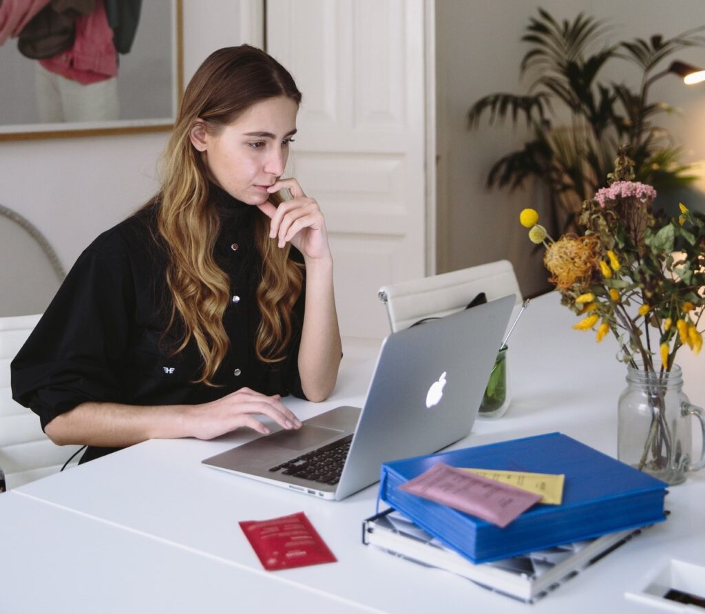 Woman working at a computer with books, a case, and