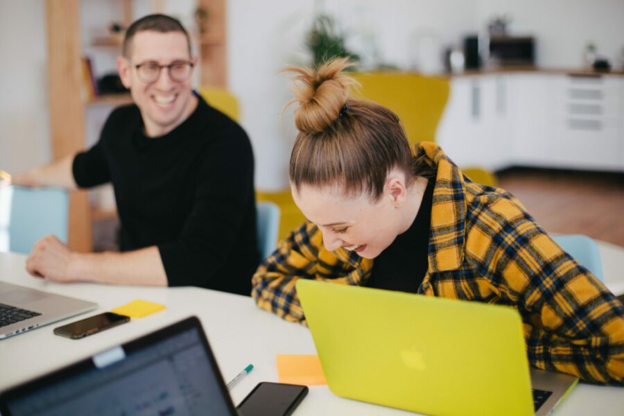 Two employees working at a desk and laughing.