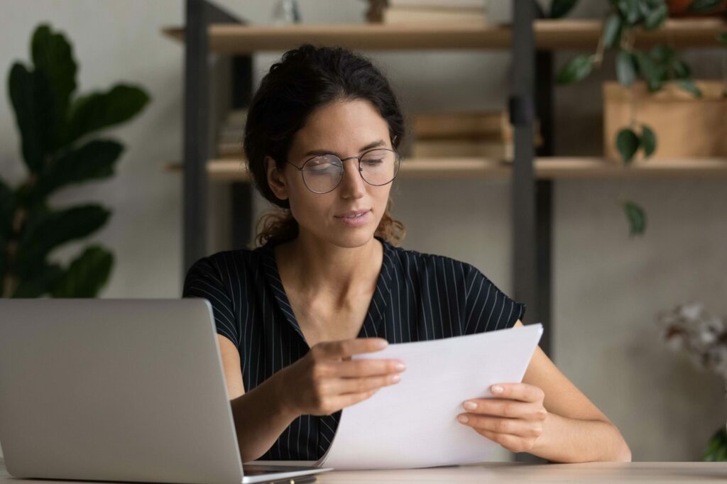 A woman is reading a cover letter while seated at her computer.