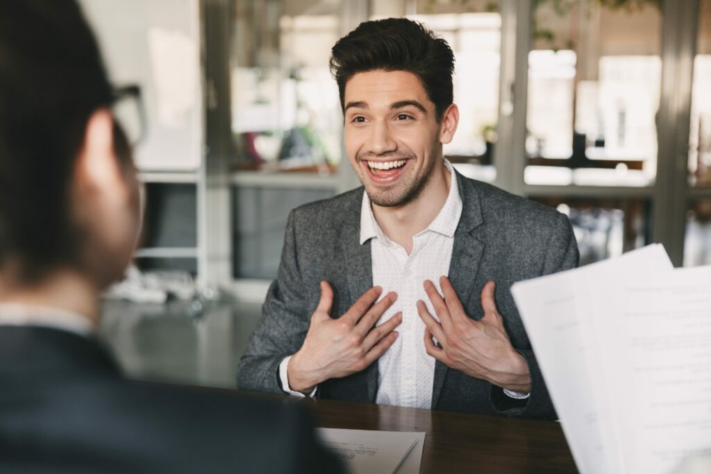 Caucasian man 30s smiling during job interview with employees in office