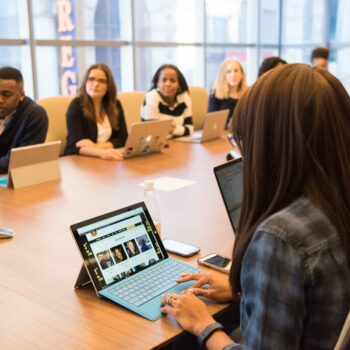 Men and women of different ages and races sit around a large conference table during a meeting