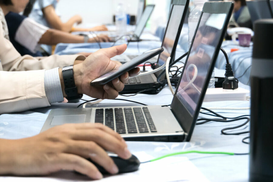 Closeup of (hands and arms only) of people working on laptops together.