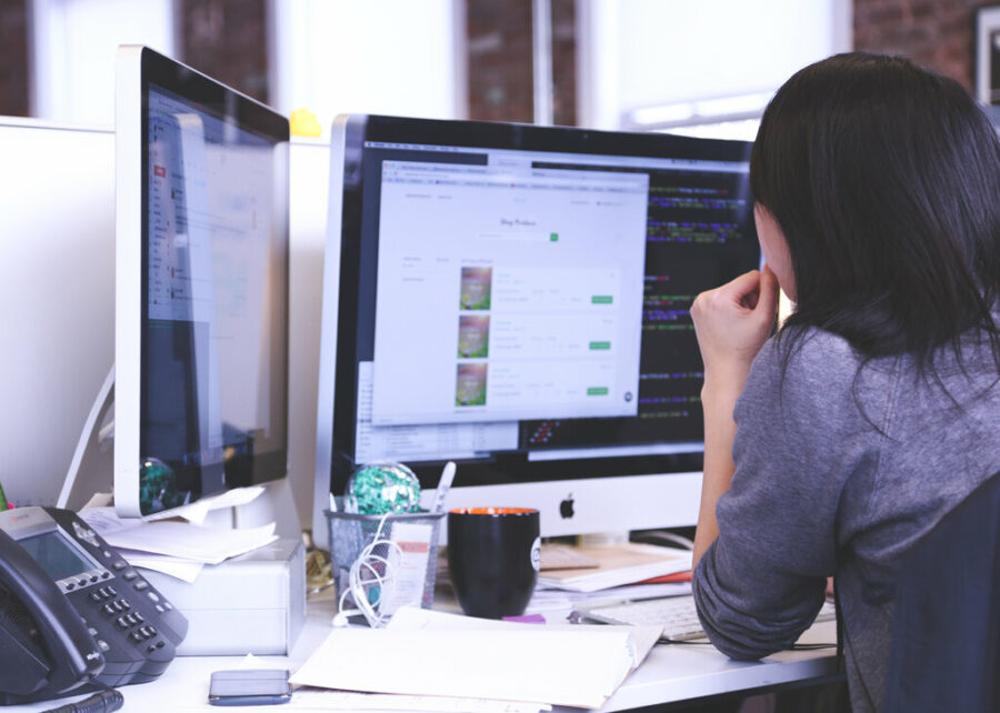 Web developer sitting at desk with two computer screens