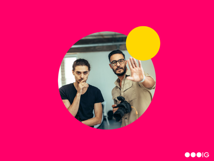 Circle cropped image of a male creative director explaining his vision to another man. Yellow accent circle. Magenta background.