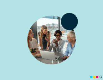 Circle crop photo of four women smiling and working around a computer. Navy blue accent circle. Light blue background.