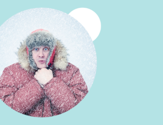 Man in snow parka surrounded by snow against a pale ice blue background What is a Hiring Freeze, and How to Respond to One as a Hiring Manager